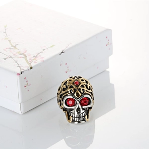 Detailed close-up of a punk skull ring featuring gold patterns and red gemstone eyes
