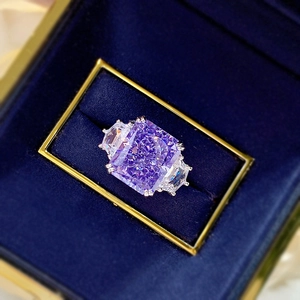 Luxury ring with rectangular purple stone and side diamonds in a blue velvet box