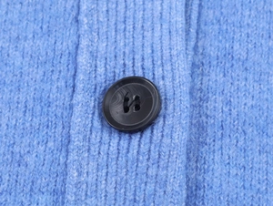Dettaglio della trama in maglia a coste blu con un bottone nero opaco a quattro fori