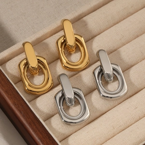 Interlocking geometric pendant earrings in gold and silver finish on a velvet tray