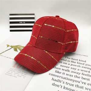 Detail shot of the red baseball cap with golden horizontal stripes and adjustable strap
