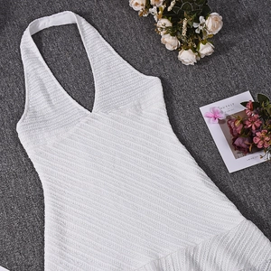 Détail d'une robe courte blanche dos nu en maille texturée avec ourlet à volants
