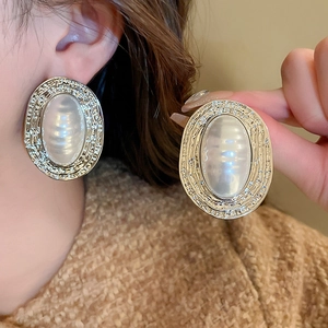 Detail of vintage gold textured oval earrings with inlaid white pearlescent center