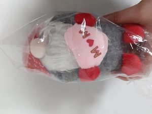Detail of plush Mother's Day gnome with MOM heart embroidery in transparent packaging