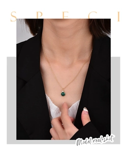 Minimalist gold necklace featuring a round green malachite pendant worn by a model