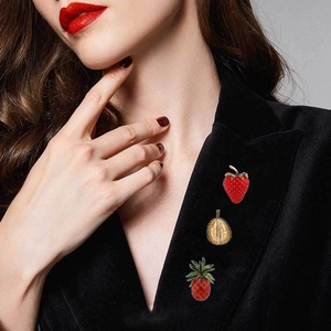 Detailed shot of creative fruit brooches strawberry and durian on black blazer lapel