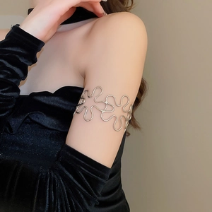 Close-up of a silver hollow flower arm cuff on a model wearing black velvet attire