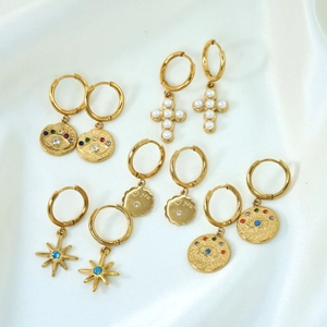 Detail of gold hoop earring set with evil eye charms, pearls, and starburst accents