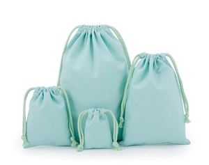 Detail of mint green drawstring cotton pouches in multiple sizes on white background