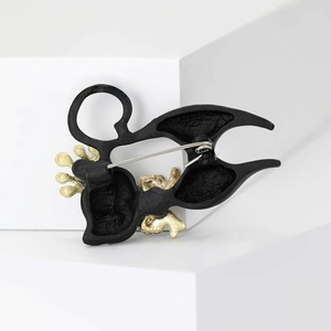 Creative black enamel cat brooch with gold accents on a clean white geometric background