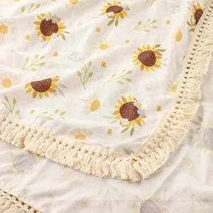 Detailed view of sunflower print cotton baby blanket featuring delicate cream fringe edges