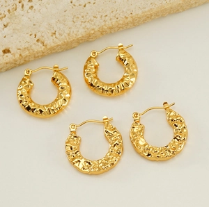 Detail of 18K gold plated earrings with hammered lava texture on stone surface