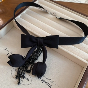 Detail of black ribbon choker featuring fabric tulip petals and beaded tassels on tray
