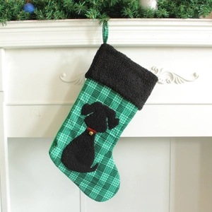 Chaussette de Noël à carreaux avec motif chien suspendue sur une cheminée blanche