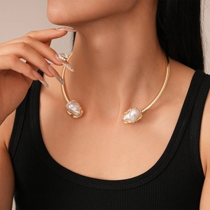 Close-up of a minimalist gold metal collar with baroque pearls on a female model