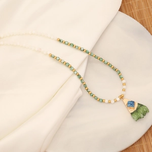 Natural stone heart necklace with green beads on a white silk and marble background