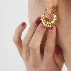 Detailed close-up of golden hollow croissant hoop earrings with twisted rope texture