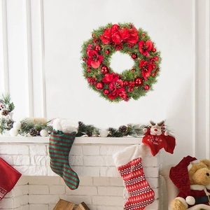 Christmas wreath with red flowers and a large bow hanging above a white brick fireplace
