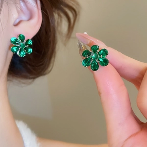 Macro shot of silver stud earrings featuring green zirconia flower petals and crystals