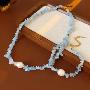 Aquamarine and pearl necklace with golden clasp displayed on a wooden jewelry tray