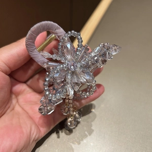Detail of beaded crystal flower hair claw with dangling tassel and purple fabric wrap