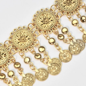 Detail of vintage gold metal waist chain with hollow flower patterns and coin tassels
