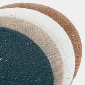 Detailed close-up of glitter knit beret fabric featuring shiny sequins and metallic yarn
