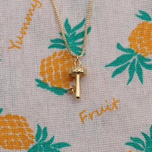 French retro gold mushroom pendant necklace on linen background with artistic textures