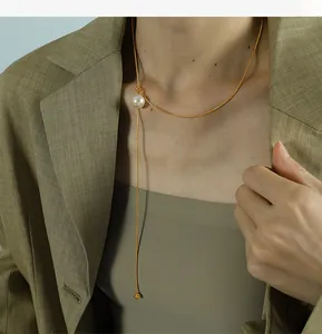 Detail einer 18K Gold Schlangenkette mit Glasperlenanhänger, von einem Model getragen