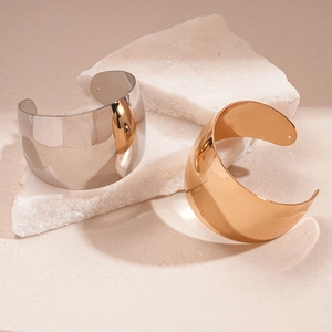 Polished gold and silver chunky open metal arm cuffs on white mineral stone display