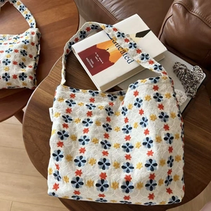 Detailed close-up of floral embroidery on a white linen canvas shoulder bag on a table