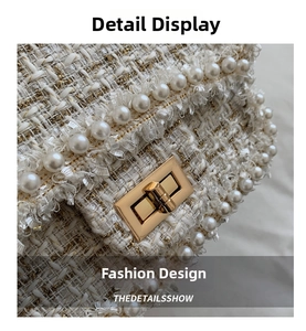 Detailed macro view of woven tweed fabric with elegant white pearls and golden twist lock