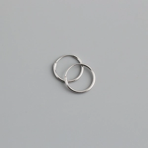 Detailed macro view of minimalist S925 sterling silver hoop earrings on a grey background