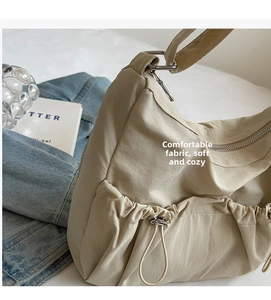 Detail of beige nylon crossbody bag with soft fabric texture and drawstring side pocket