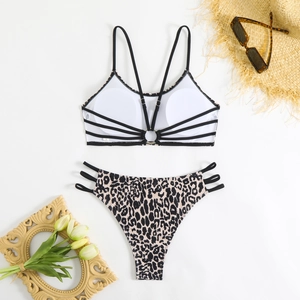 Flat lay of white bikini top with ring detail and leopard print bottoms on summer props