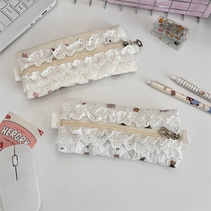 Detailed macro of floral quilted pencil case with white lace trim and flower zipper pull