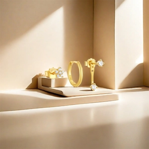 Detailed view of S925 silver gold-plated earring set with white zircon on a beige stand