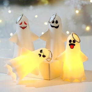 Close-up of four glowing ghost keychains with cartoon faces for Halloween party decor