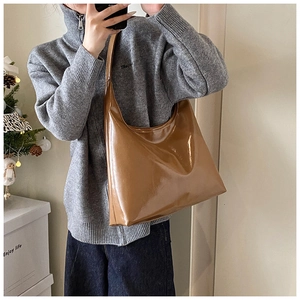 Close-up of a brown polished underarm tote bag shown on a model in a cozy winter setting