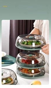 Vertical stack of clear multi-layer food covers with green non-slip handles and base