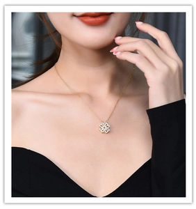 Close-up of golden clover necklace with four heart shapes and sparkling crystals on model