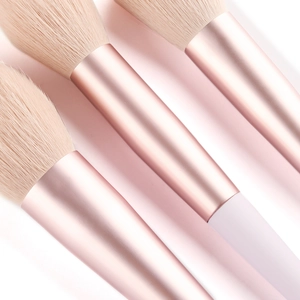Gros plan des poils doux beige amande et de la virole en métal or rose du pinceau