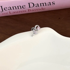 Macro shot of silver crescent moon and star earring with pink cubic zirconia on a desk