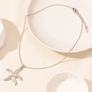 Detailed close-up of a silver stainless steel starfish pendant necklace on a white tray