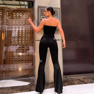 Detail of black strapless jumpsuit featuring sparkling rhinestones and flared leg fit