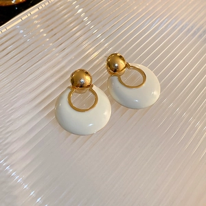 Detail of French luxury hoop earrings with gold studs and cream enamel rings