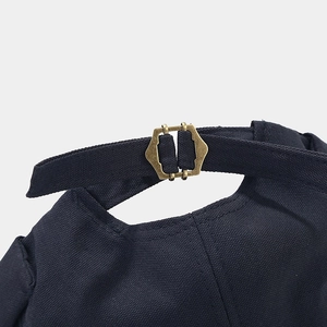 Close-up of retro bronze buckle and canvas strap adjustment on navy brimless dock cap