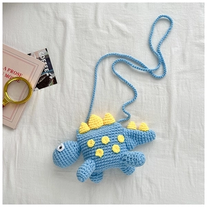 Close-up of handmade crochet dinosaur crossbody bag showing fine knit texture and yellow spikes