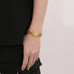 Close-up of men's golden Cuban chain bracelet with rectangular buckle on wrist