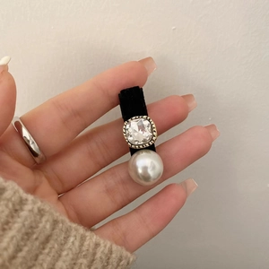 Détail d'une barrette en velours ornée d'un strass carré et d'une perle